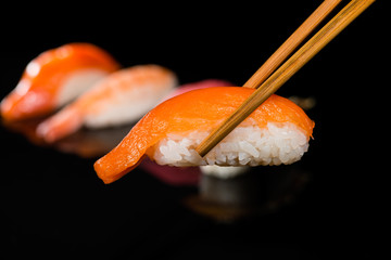 close-up nigiri with salmon on chop sticks