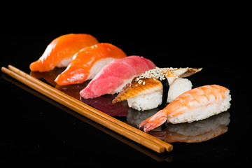assortment of nigiri sushi on a dark background with chop sticks