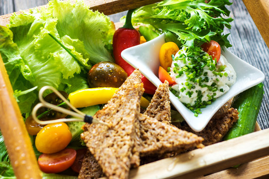 Picnic basket with delicious crispy vegetables, toasted wholemeal bread and sauce