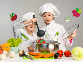 cooking little boy and girl looking in pan 