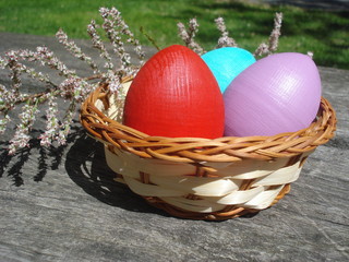 Colorful Easter eggs in wicker little basket on wooden table
