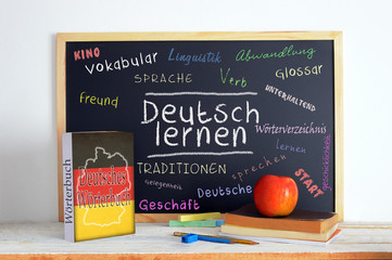 Blackboard in a German classroom with the message LEARN GERMAN and some text - obrazy, fototapety, plakaty