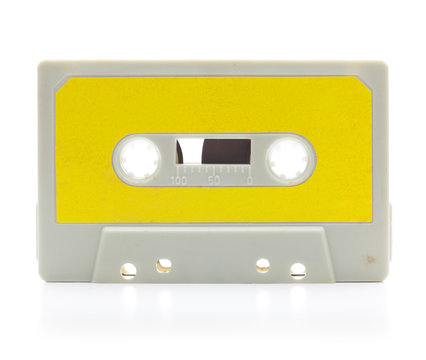 Early 70's cassette tape isolated on white with slight reflection. Yellow label.