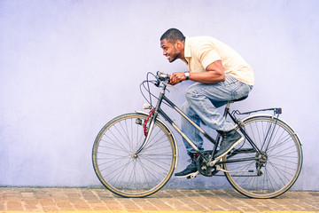 Fototapeta na wymiar Black American African man in funny scene with locked old bike - Young afroamerican guy riding vintage bicycle with red padlock safe chained to wheel - Fun concept of cycle theft and security tools 