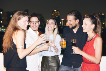 Happy people on rooftop party. Cityscape view at night.