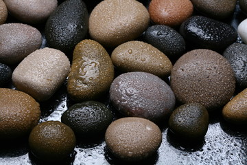 Fototapeta na wymiar Wet colored stones background, dark pebbles. 