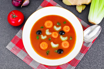 Carrot Tomato Soup in Plate. Behind lie on the soup ingredients,