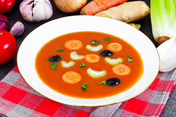 Carrot Tomato Soup in Plate. Behind lie on the soup ingredients,