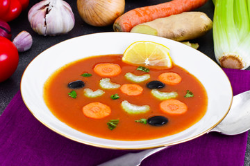 Carrot Tomato Soup in Plate. Behind lie on the soup ingredients,