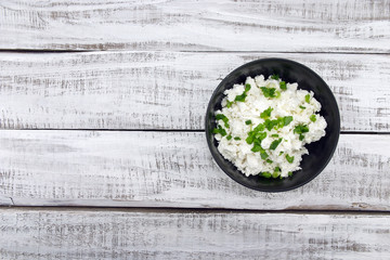 Cottage cheese with chives in black ceramic bowl 