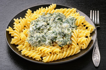 Italian pasta with spinach sauce  on black plate.