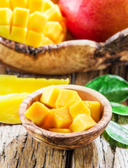 Mango fruit and mango cubes on the wooden table.