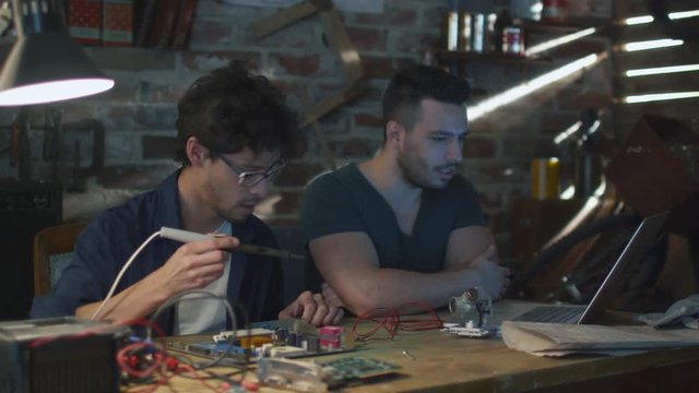 Two students are studying electronics and soldering in a garage. Shot on RED Cinema Camera.