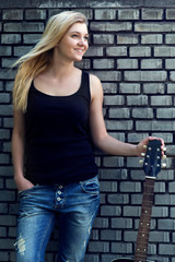 Fototapeta na wymiar portrait of a woman with a guitar near brick wall