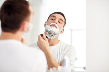 man shaving beard with razor blade at bathroom - Powered by Adobe