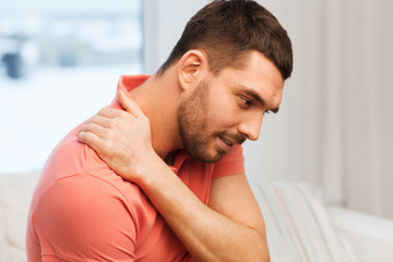 unhappy man suffering from neck pain at home