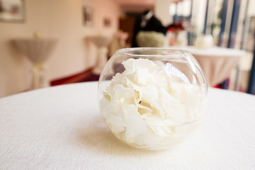 Wedding table composition with petals of roses in round vase