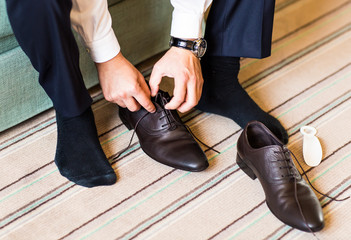 Close-up young man tying elegant shoes indoors