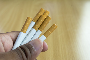 Hand hold cigarettes on wooden background