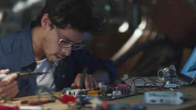 Student is studying electronics and soldering a circuit board in a garage. Shot on RED Cinema Camera.