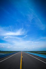 Empty road and the yellow traffic lines with blue sky.