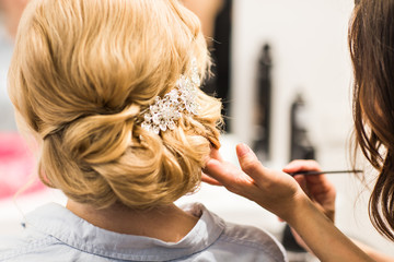 Fototapeta premium Hair stylist makes the bride before a wedding