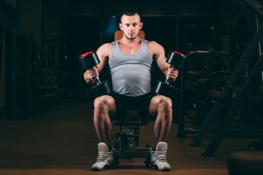 sport, bodybuilding, weightlifting, lifestyle and people concept - young man with dumbbells flexing muscles in gym