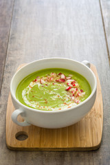 Peas cream with radishes on rustic wood
