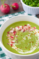 Peas cream with radishes on rustic wood
