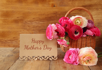 flowers next to card, on wooden table. 