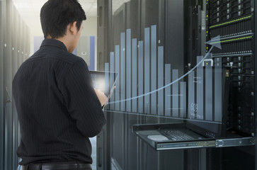 Fototapeta premium Man working in data center and use tablet for analyze system