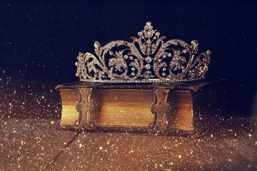 low key image of beautiful diamond queen crown on old book