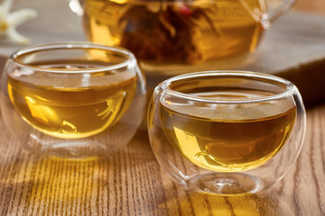 Two glass cups and teapot with green tea