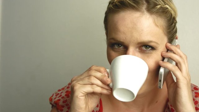 junge frau trinkt kaffee, telefoniert und schaut verliebt in kamera 