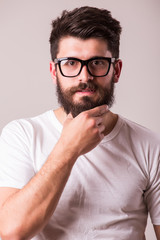 Fototapeta premium Face portrait of bearded man in glasses with hand on beard against white background