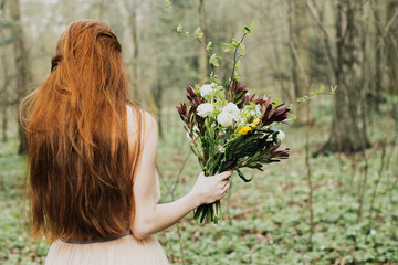 rudowłosa kobieta z tyłu z bukietem w ręku