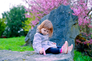 A little artist is drawing on the rocks with her chalk