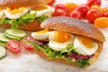 Sandwich with egg and vegetables on wooden background