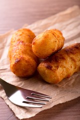Fork in front of three fried crispy potato croquettes
