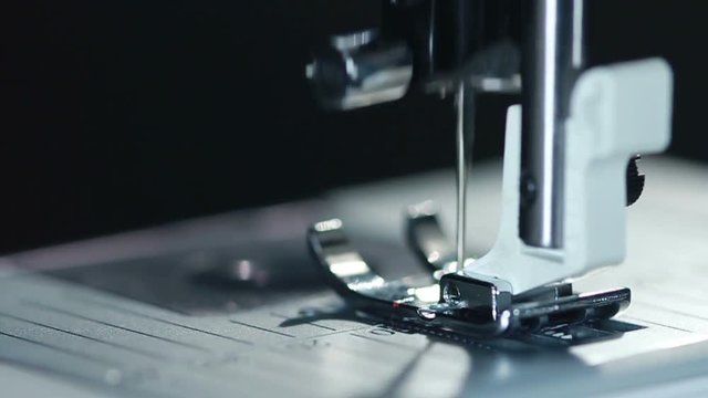 Equipment at textile factory. Closeup. Sewing needle in slow motion. Sewing machine needle work process. Sewing needle working. Industrial sewing machine working