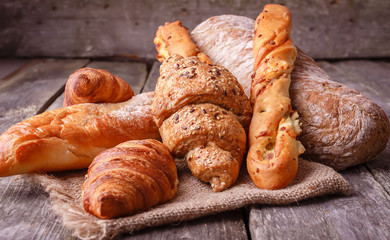 Assortment of fresh baked bread and croissants on burlap on rustic table