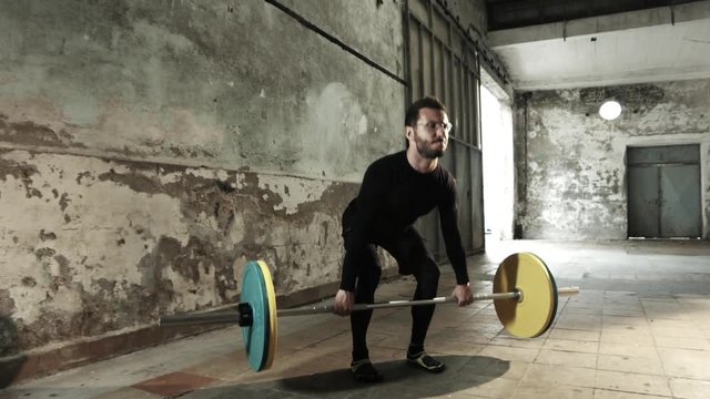 young man weight lifting workout in old industrial hall