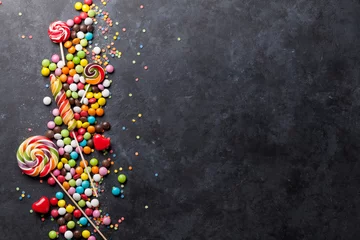 Foto op Plexiglas Kleurrijke snoepjes en lollies over steen © karandaev