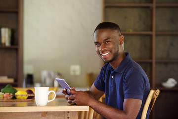 Young black guy sitting at home with a digital tablet