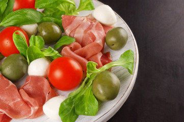 Italian appetizer: prosciutto, mozzarella, cherry tomatoes, lett