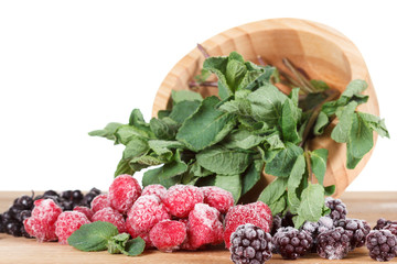 Frozen berries on a wooden table, covered with ice