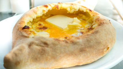 Adjaruli khachapuri, filled with cheese and topped with a raw eg
