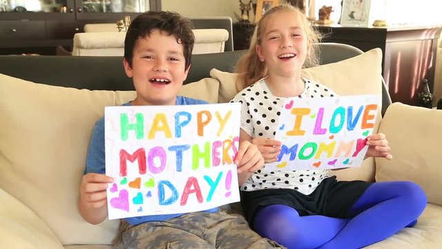 Happy cute little girl and boy smiling to a camera and showing personal notes for mothers day