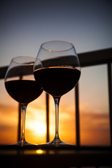 Two glasses with red wine in sunset