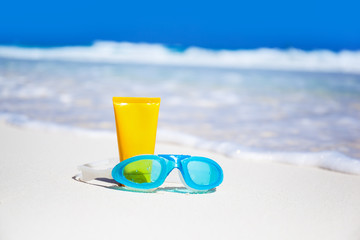 Sun screen lotion and swimming glasses on beach